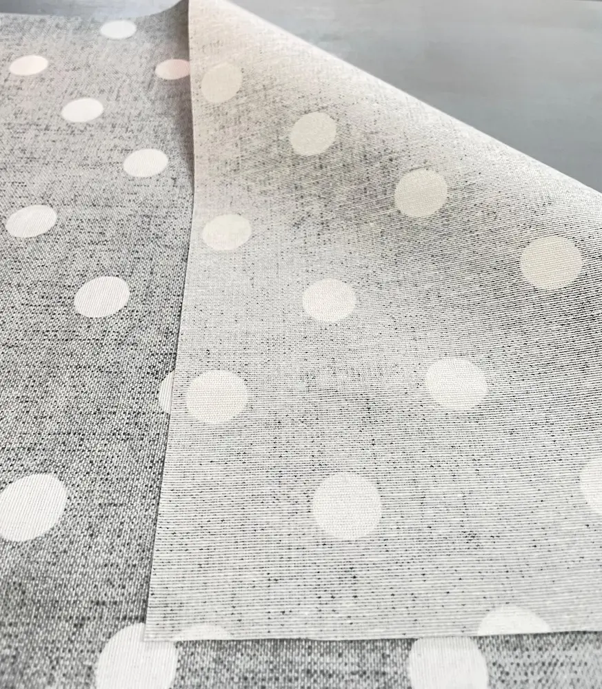 Drapierte beschichtete Baumwolle in grauer Leinen-Optik mit weißen Punkten, zeigt die matte Beschichtung und die helle Stoffrückseite.