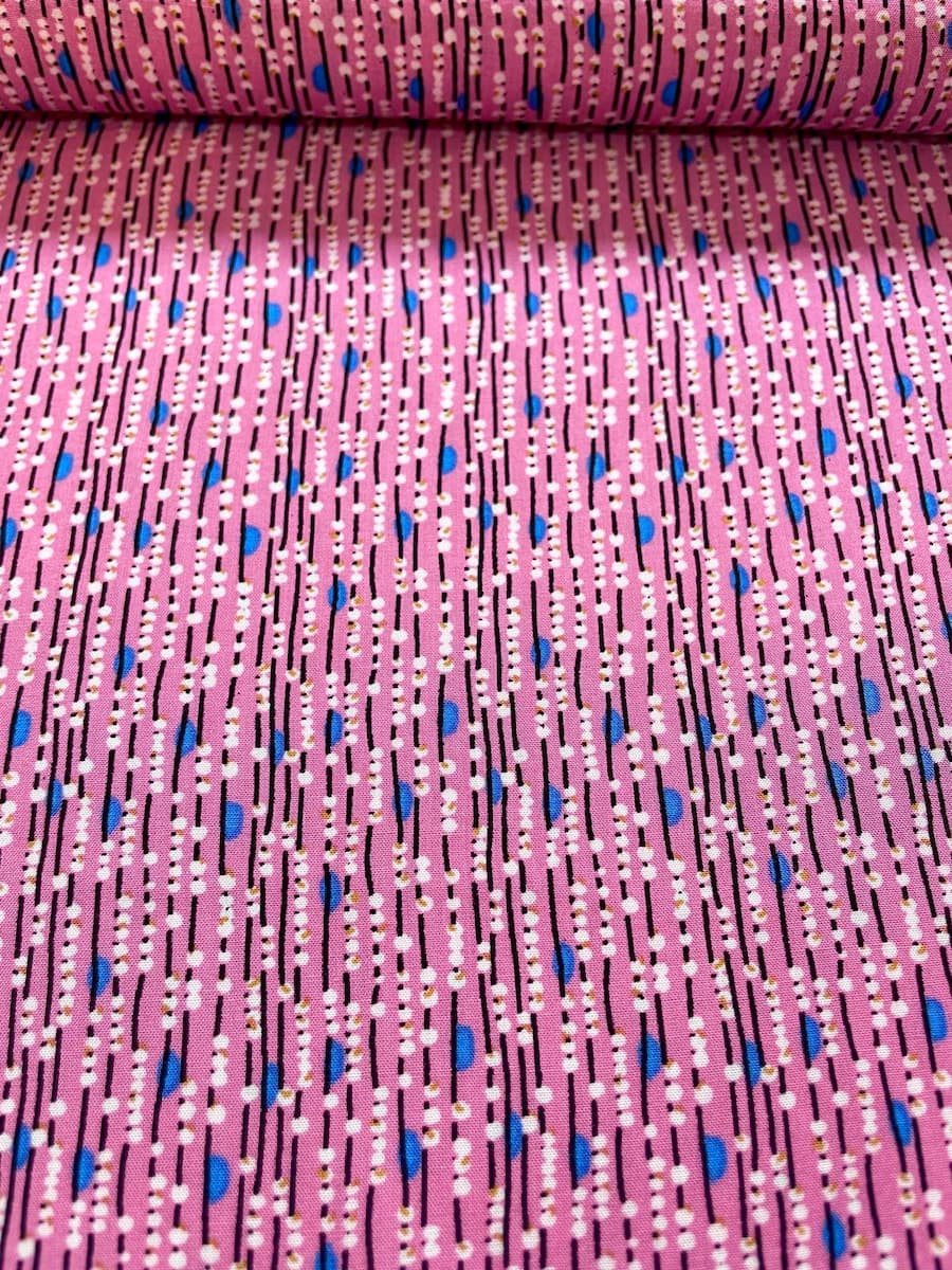 Nahaufnahme eines pinken Viskosestoffs mit vertikalem Linienmuster, weißen Punkten und blauen Details.
