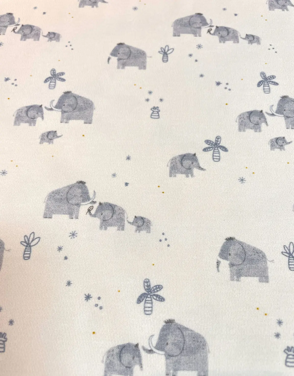 Weicher Jersey-Stoff in Weiß mit graublauen Elefanten-Motiven, kleinen Palmen und Sternen – ideal für maritime oder neutrale Babykleidung.