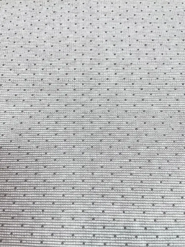 Nachhaltiger Bio-Jacquard-Strickstoff in hellem Grau mit einem gleichmäßigen, feinen Punktemuster in Weiß. Die hochwertige Strickstruktur ist im Detail erkennbar. Der blickdichte und weiche Stoff aus Bio-Baumwolle eignet sich perfekt für minimalistische D