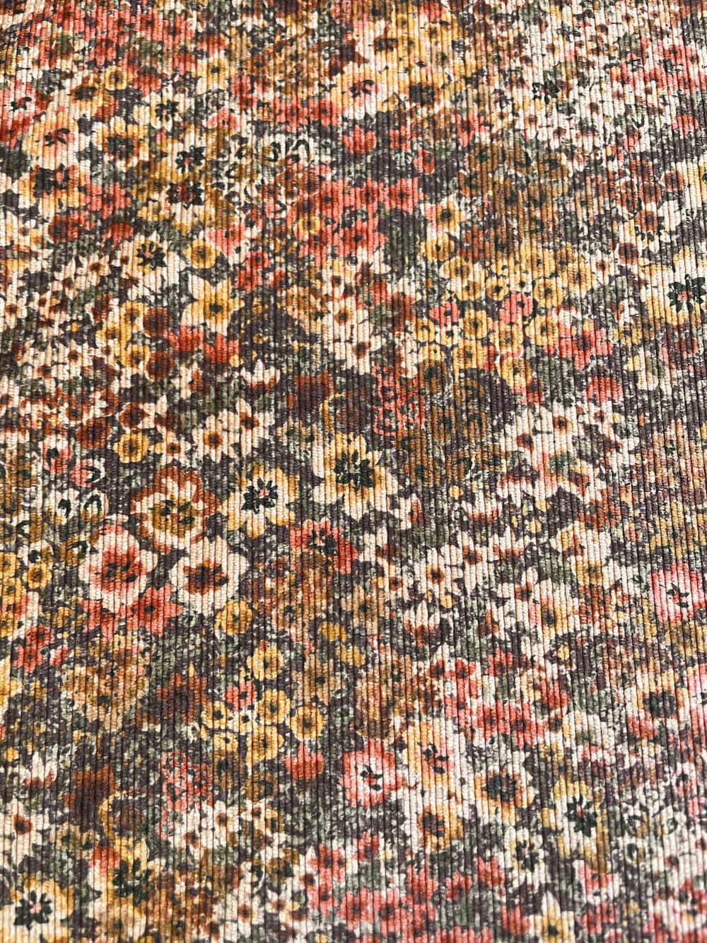 Feincord-Jacquard-Meterware (87 % Polyester, 9 % Polyamid, 4 % Elasthan) mit feinem Rippenmuster und einem herbstlichen Retro-Blumenmuster in Braun, Rosa und Gelb.