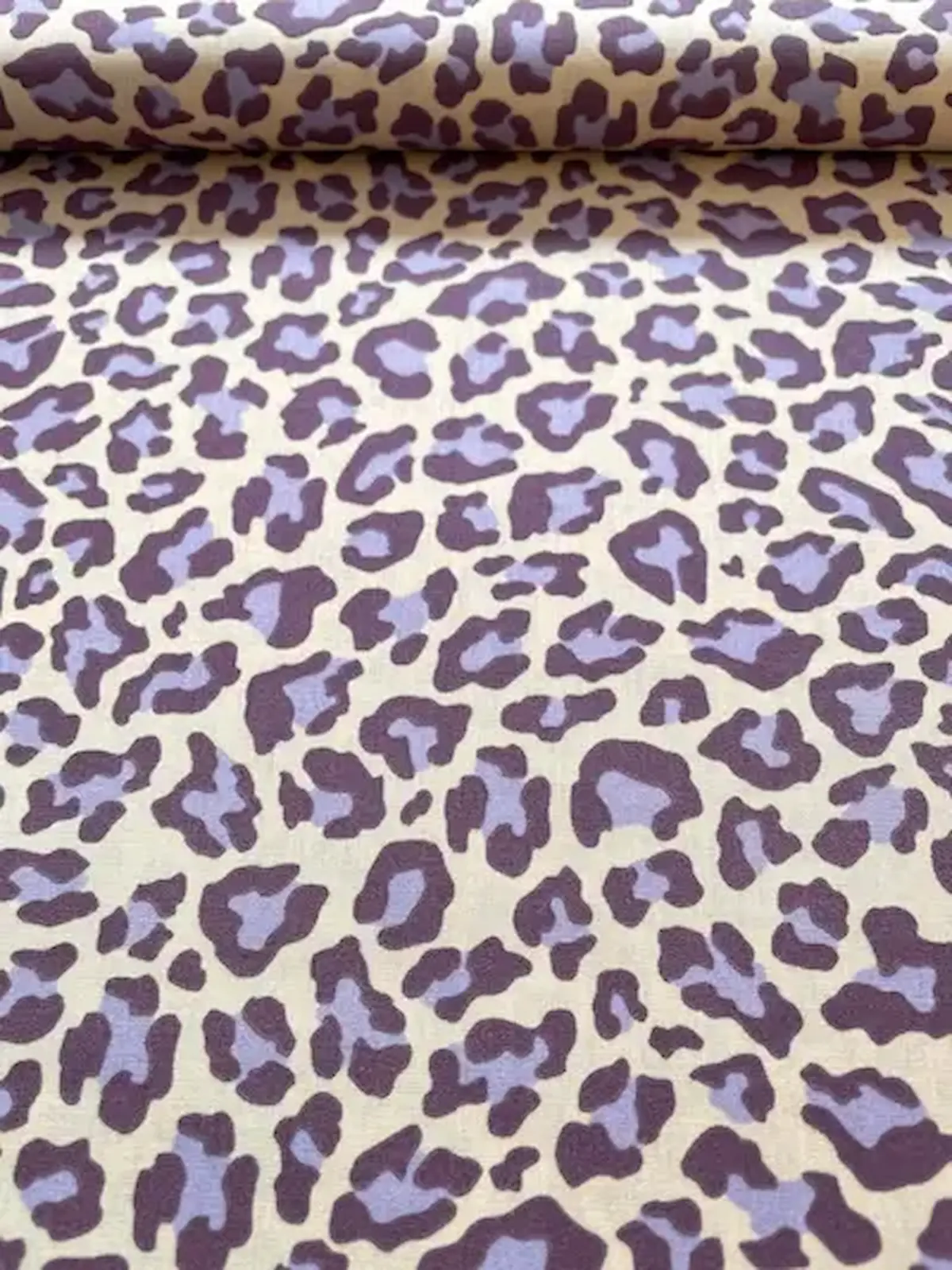Hochwertiger Baumwollstoff mit modernem Leopardenmuster in Flieder und dunklem Lila auf hellem Hintergrund.