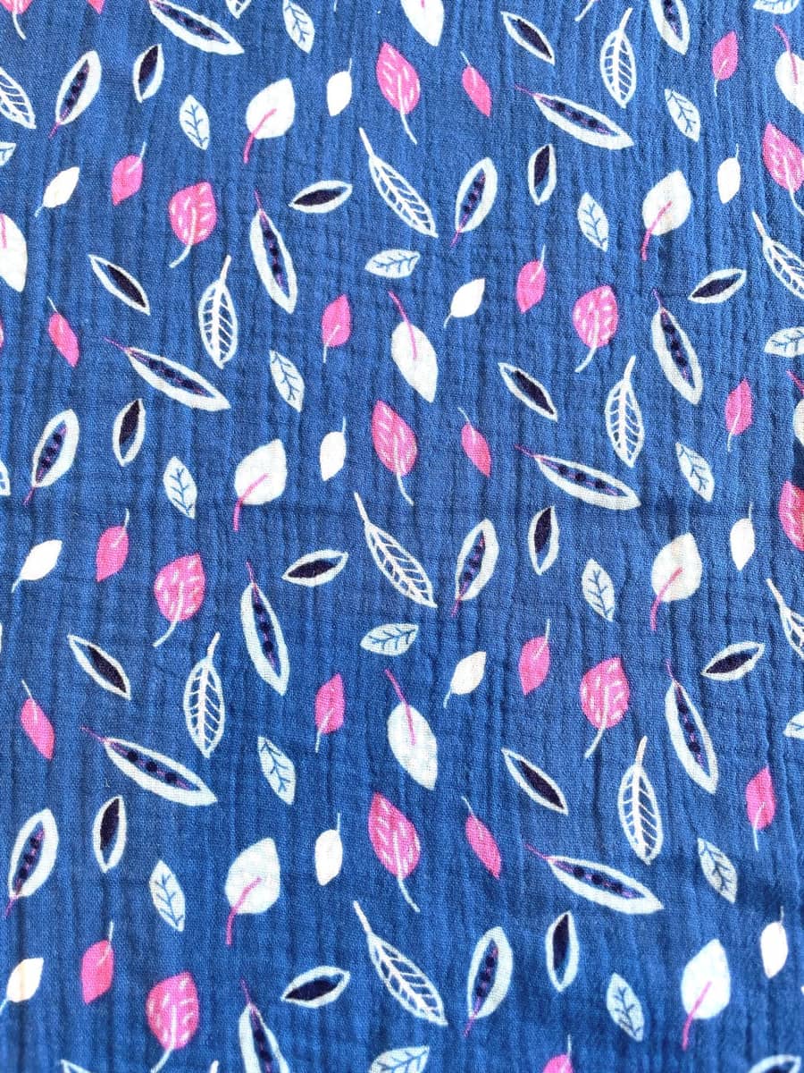 Dunkelblauer Musselin-Stoff aus 100% Baumwolle mit feinem Blatt-Print in Weiß und Pink, charakteristische Crinkle-Struktur, 130g pro Quadratmeter.