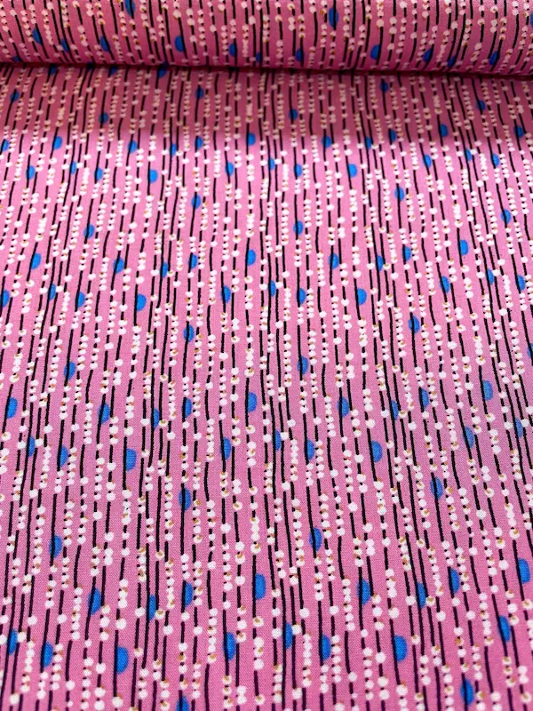 Nahaufnahme eines pinken Viskosestoffs mit vertikalem Linienmuster, weißen Punkten und blauen Details.