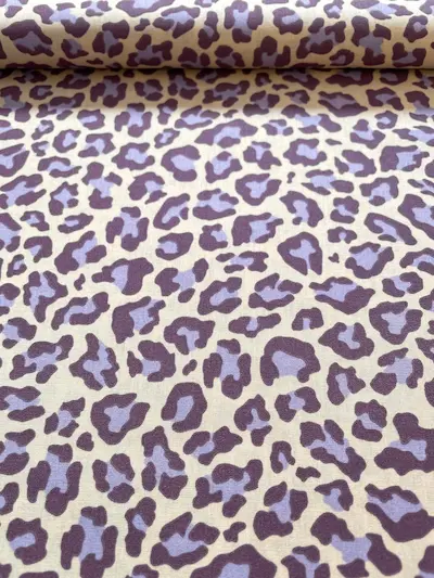 Hochwertiger Baumwollstoff mit modernem Leopardenmuster in Flieder und dunklem Lila auf hellem Hintergrund.