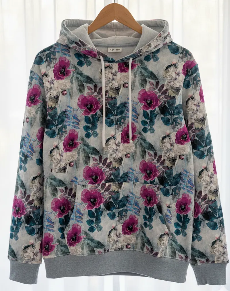 Kapuzenpullover (Hoodie) aus Sommersweat mit Mohnblumen-Print auf einem Holz-Kleiderbügel vor hellem Hintergrund.