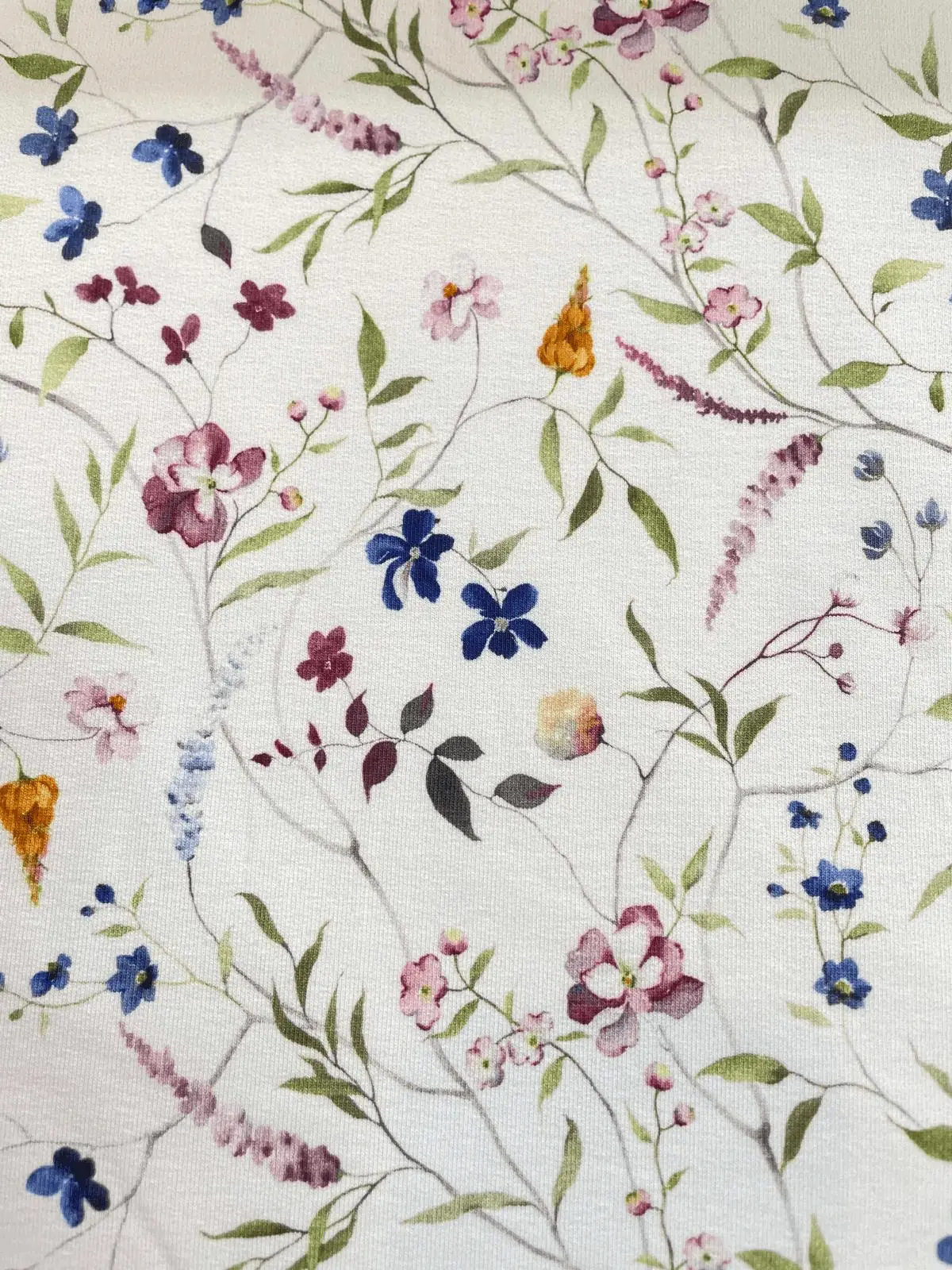 Floraler French Terry Stoff mit buntem Aquarell-Blumenmuster auf weißem Hintergrund als Meterware