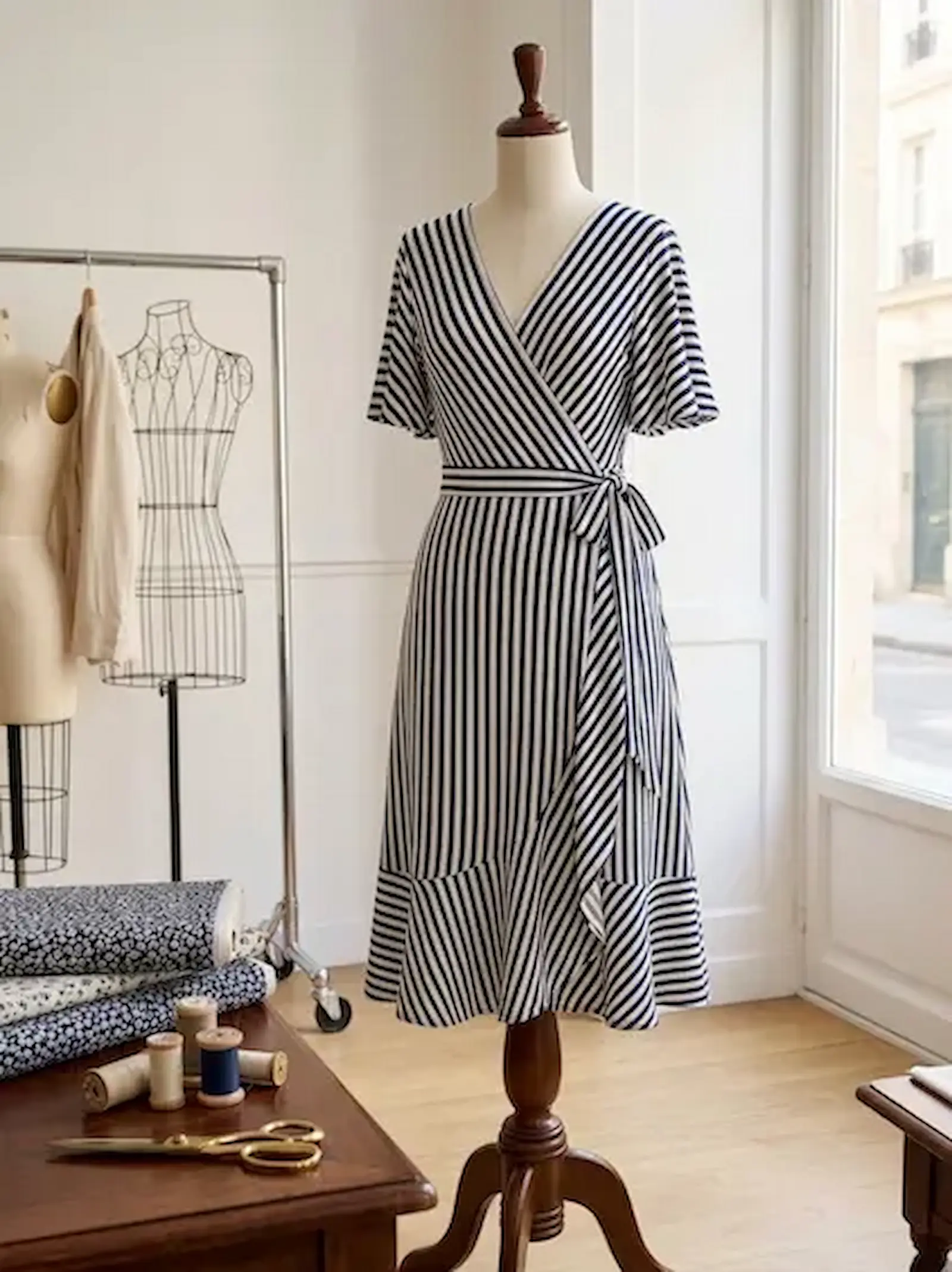 Marineblau-weiß gestreiftes Wickelkleid aus fließendem Viskosejersey auf einer Schneiderpuppe in einem hellen Schneideratelier