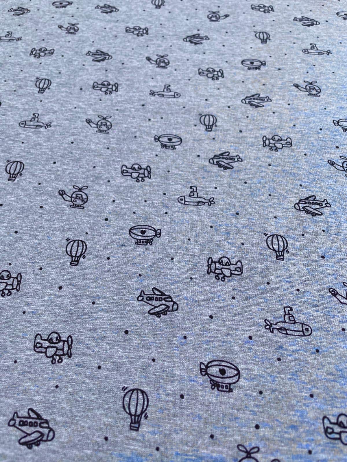 Alpenfleece Stoff Meterware in Hell-Blaugrau mit Muster aus Flugzeugen, Hubschraubern und Luftballons.