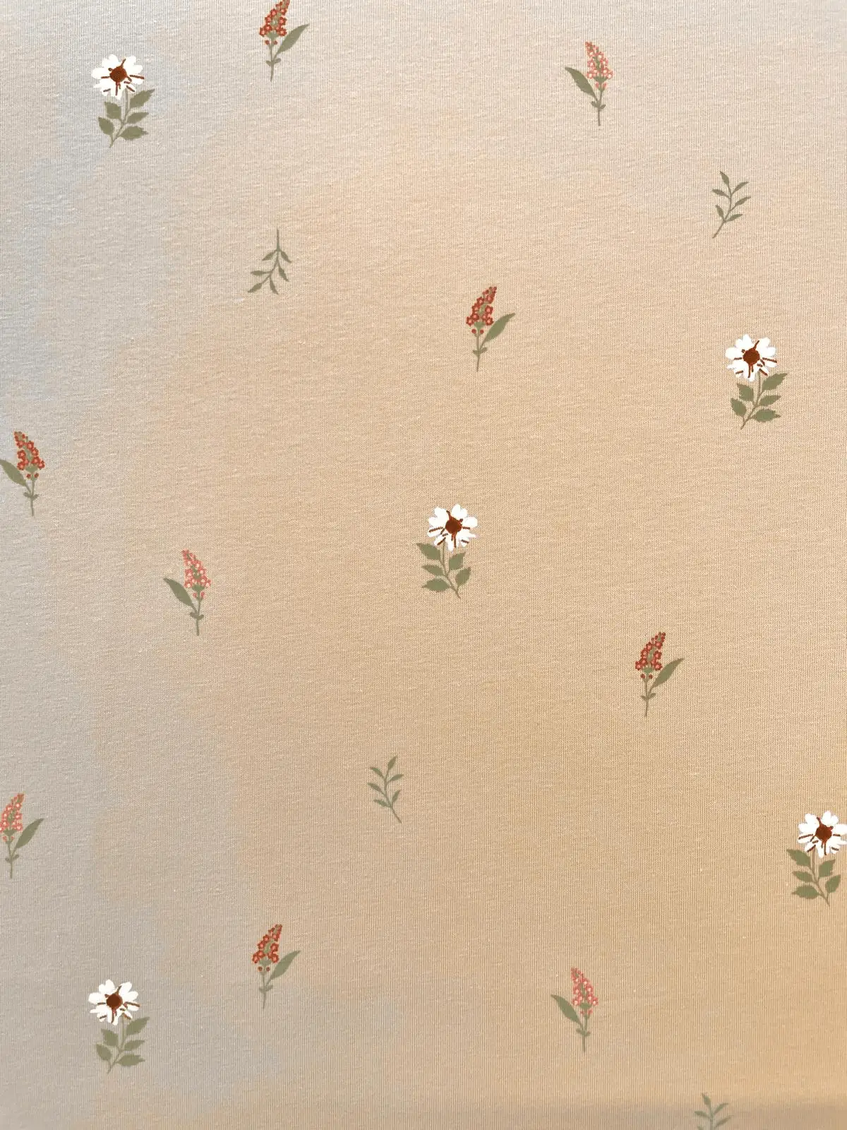 Hochwertiger Baumwolljersey in Beige bedruckt mit kleinen weißen Blumen und filigranen roten Blüten.