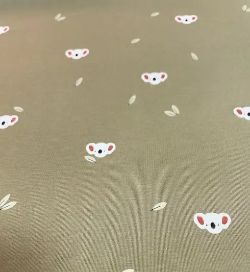 Olivgrüner Jersey-Stoff mit kleinen weißen Koalaköpfen und dezenten Blättern – minimalistisches Design für moderne Baby- und Kinderkleidung.