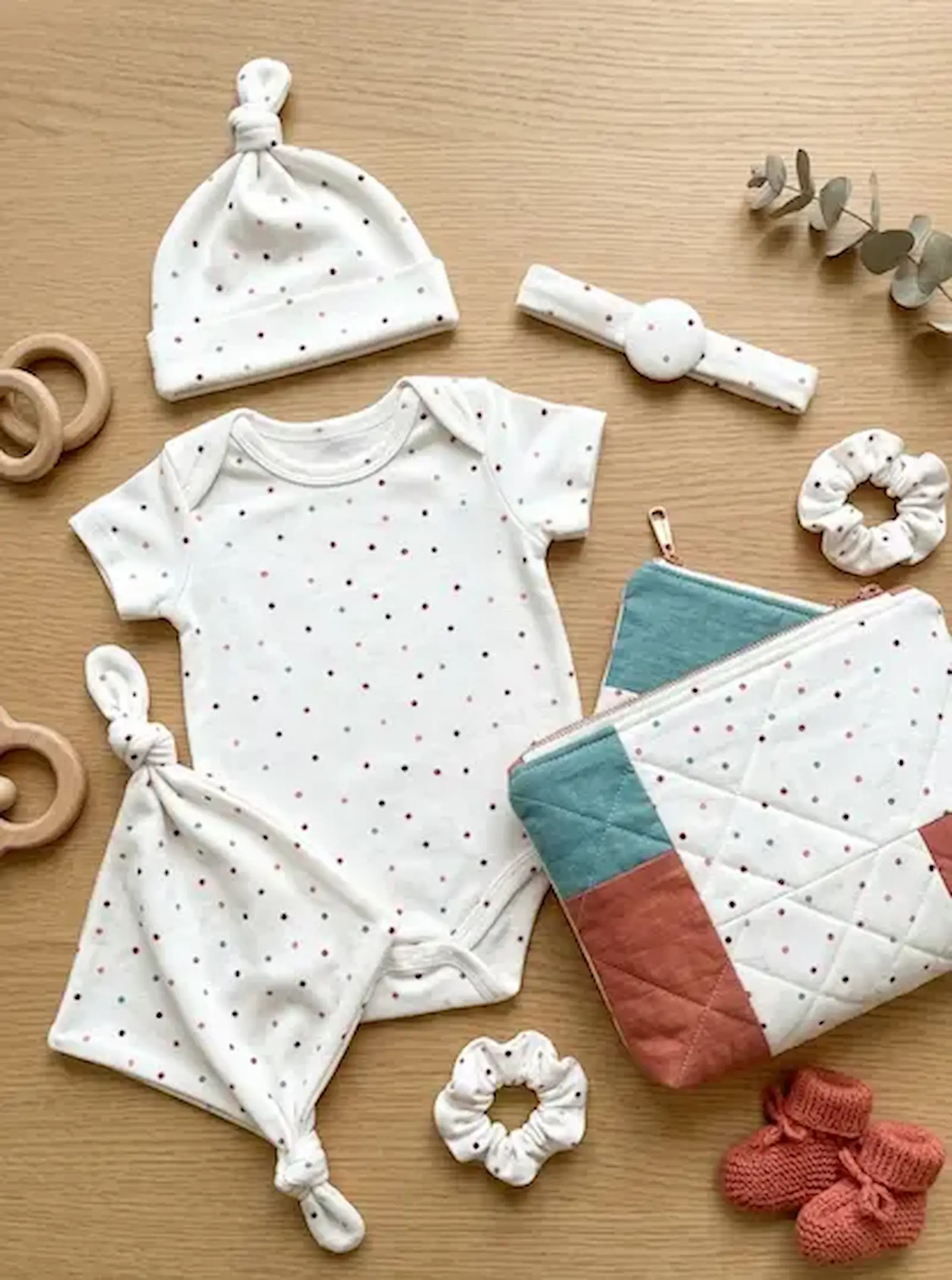 Nahaufnahme eines weißen Jersey-Stoffs mit einem Allover-Print aus kleinen, bunten Punkten; ideal für elastische Babybekleidung.