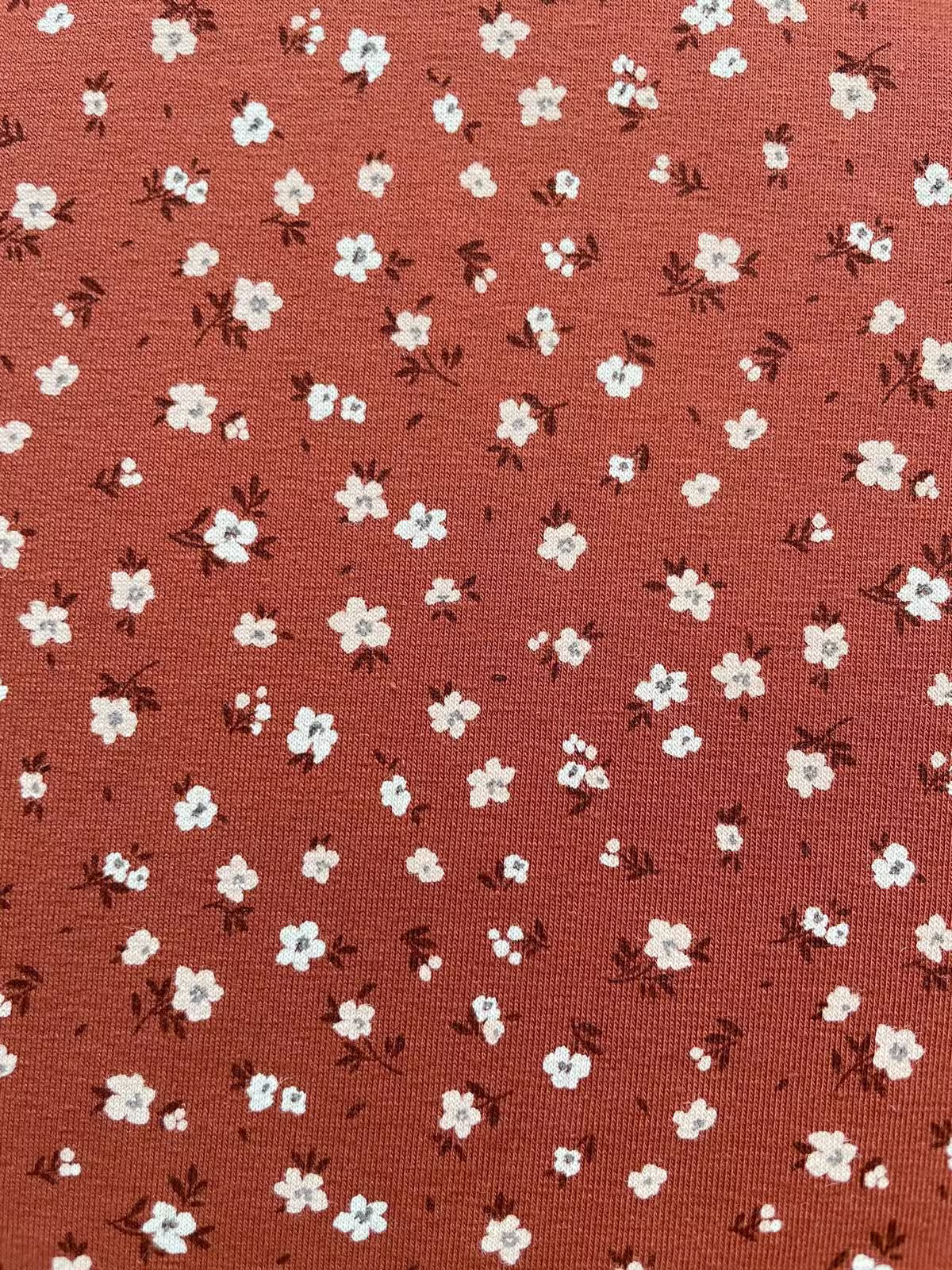 Weicher Jerseystoff in Rostbraun mit zierlichem weißen Blumenmuster, ideal für Kinderkleidung und Damenmode