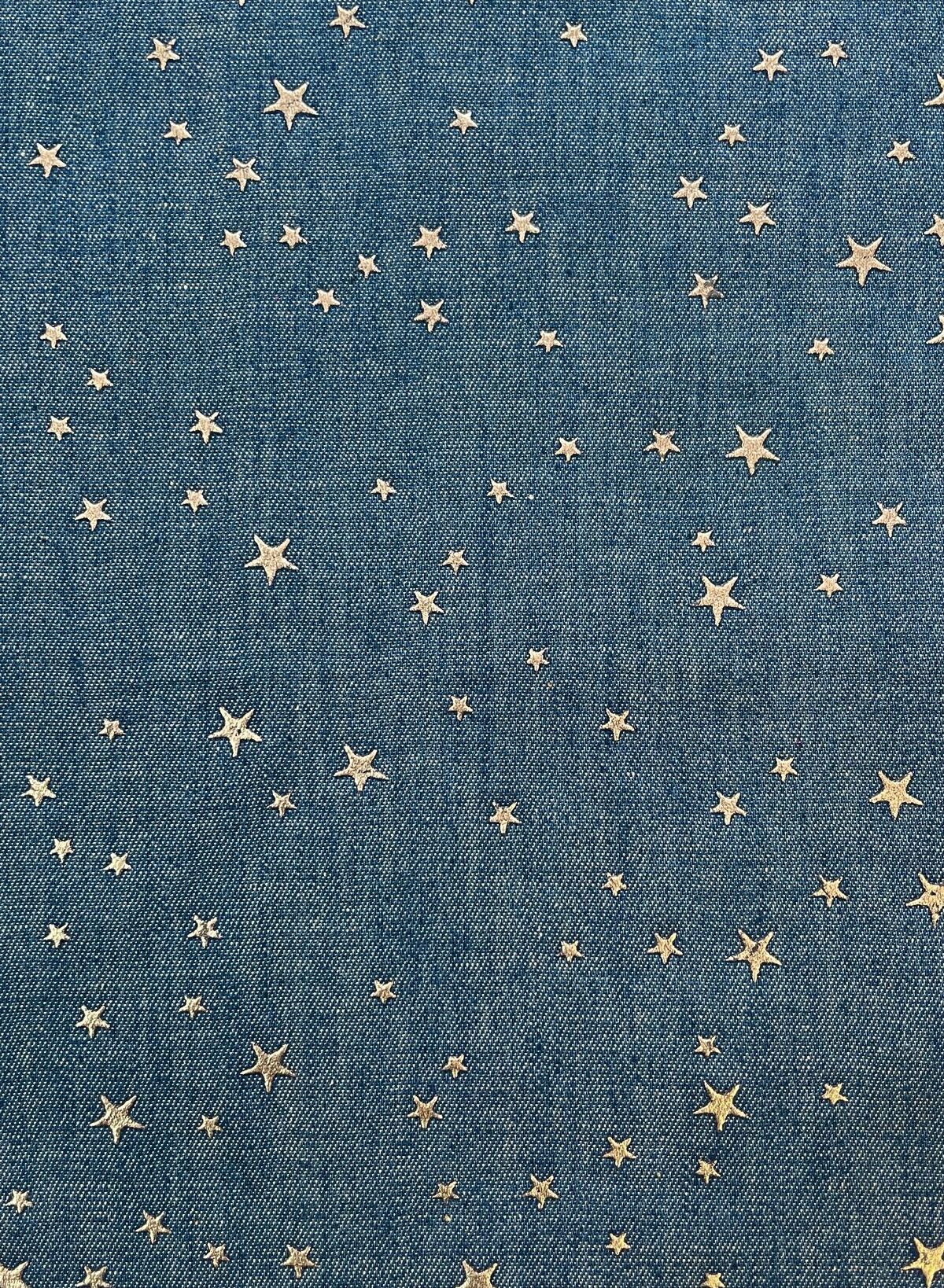 Nahaufnahme von jeansblauem Baumwollstoff mit fest aufgebrachten, silbernen Metall-Sternen. Die Sterne sind matt-glänzend ohne Glitzer, ideal für Kinderhosen und Schultüten.