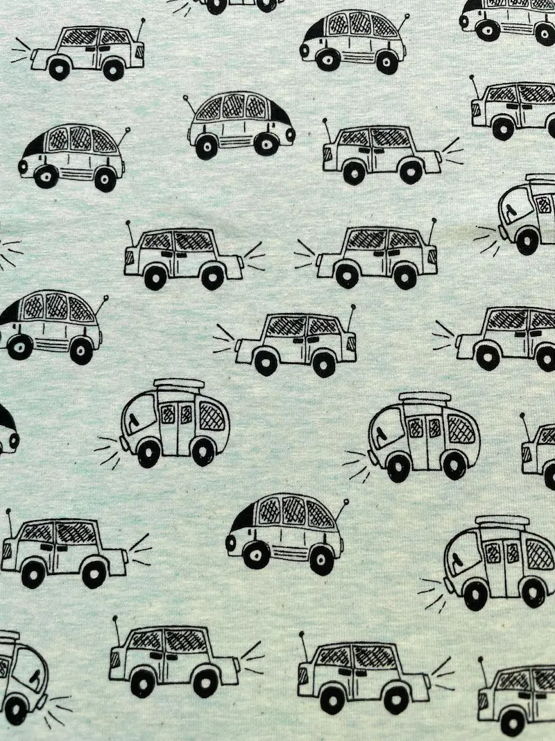 Meterware Baumwolljersey in Mint meliert mit schwarzem Muster aus handgezeichneten Retro-Autos, Käfern und Wohnwagen im Doodle-Stil für Kinderkleidung.
