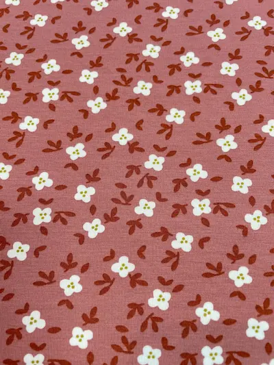 Elastischer Jersey-Stoff in Altrosa mit kleinen weißen Blüten und rostbraunen Blättern im floralen Allover-Design.