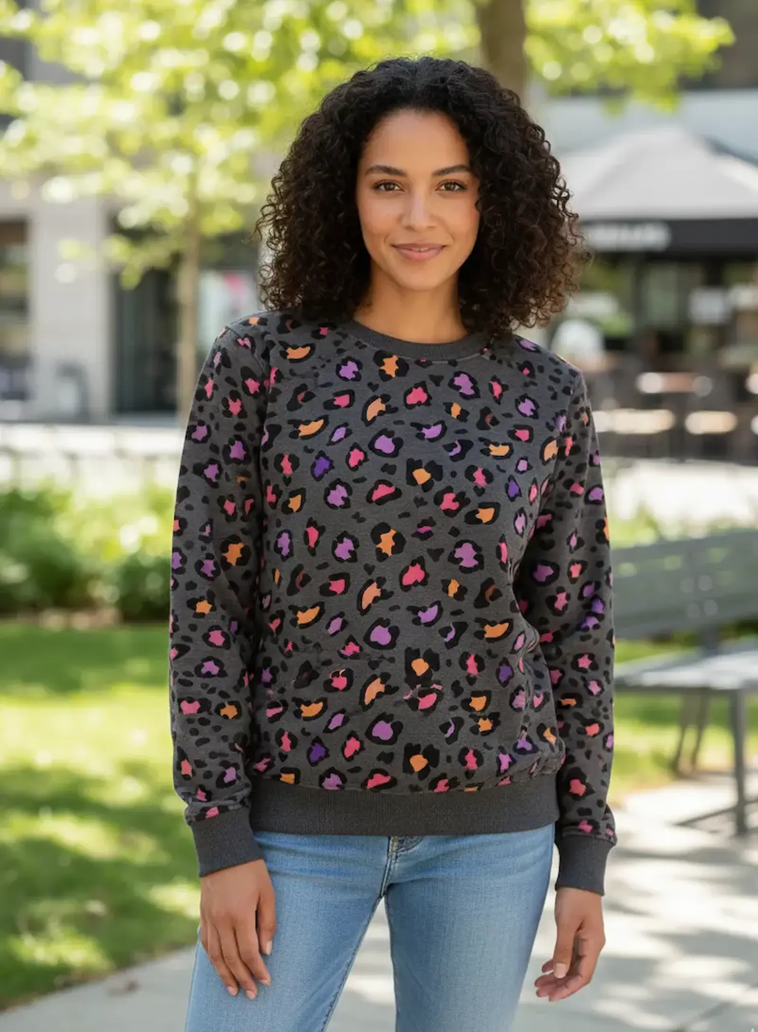 Porträt einer Frau in einem selbstgenähten Sweatshirt aus anthrazitfarbenem Sommersweat mit buntem Leo-Print. Hochwertige Meterware für Damenmode.