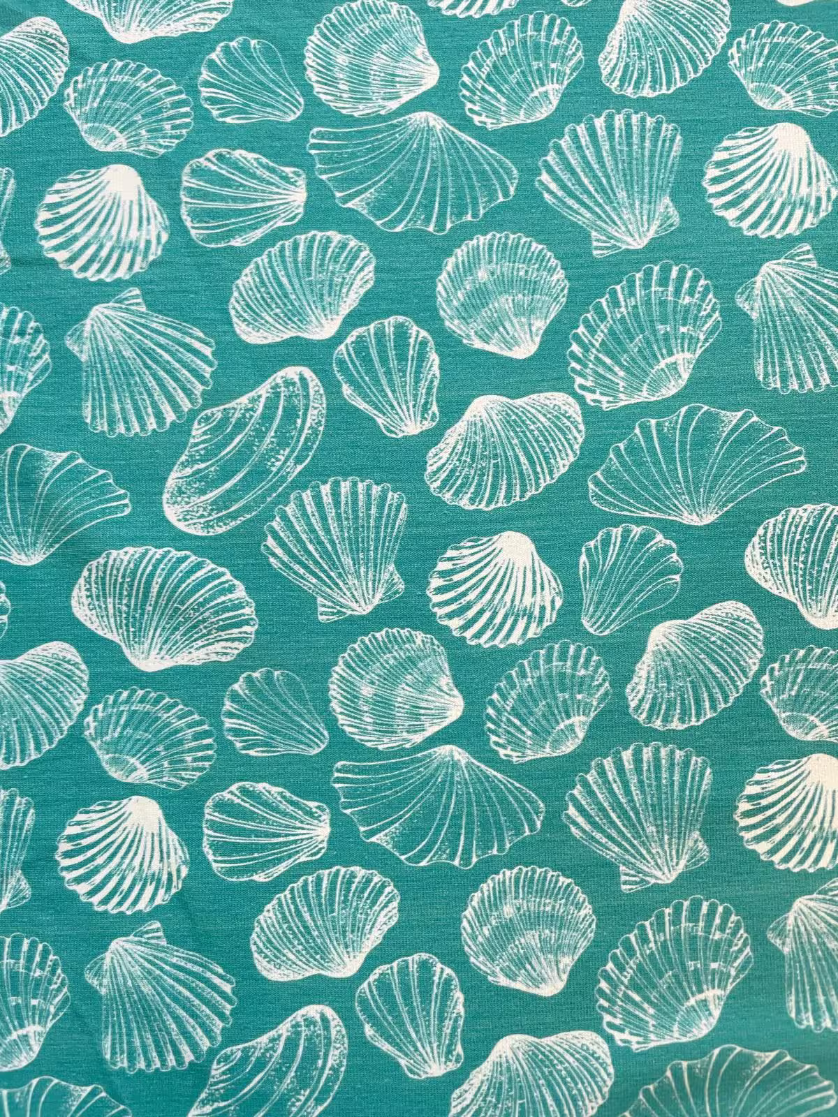 Hochwertiger Jersey-Stoff als Meterware in Petrol-Türkis bedruckt mit feinen weißen Muschel-Motiven im Stoffpfau Onlineshop.
